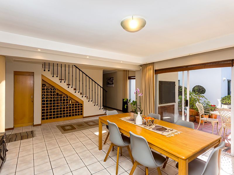 Open plan dining area featuring tiled floors, a built-in wine rack under the staircase, and sliding glass doors leading to an outdoor patio.