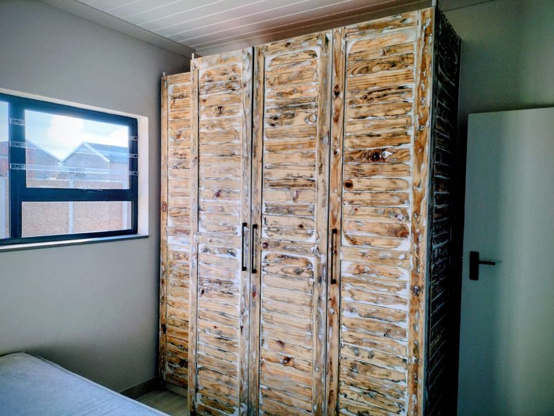 Bedroom featuring a large built-in wardrobe with a rustic wood finish and a modern aluminium window frame.