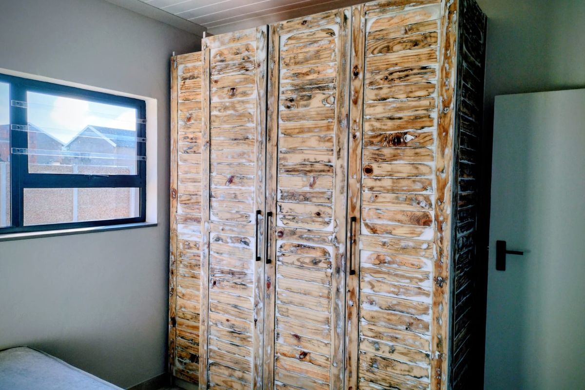 Bedroom featuring a large built-in wardrobe with a rustic wood finish and a modern aluminium window frame.