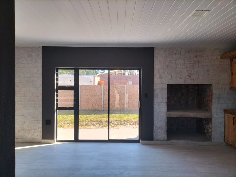 Spacious living area featuring a built-in fireplace, exposed brick accents, and large sliding glass doors providing direct access to the rear garden.