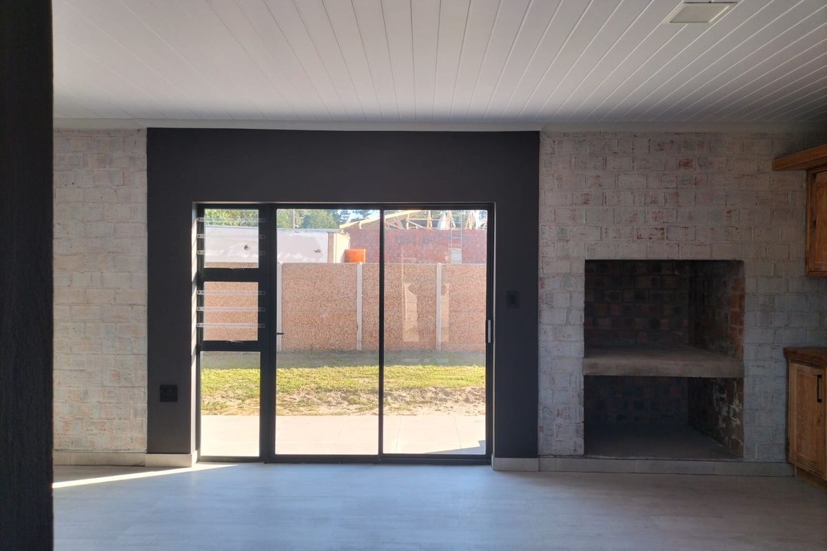 Spacious living area featuring a built-in fireplace, exposed brick accents, and large sliding glass doors providing direct access to the rear garden.