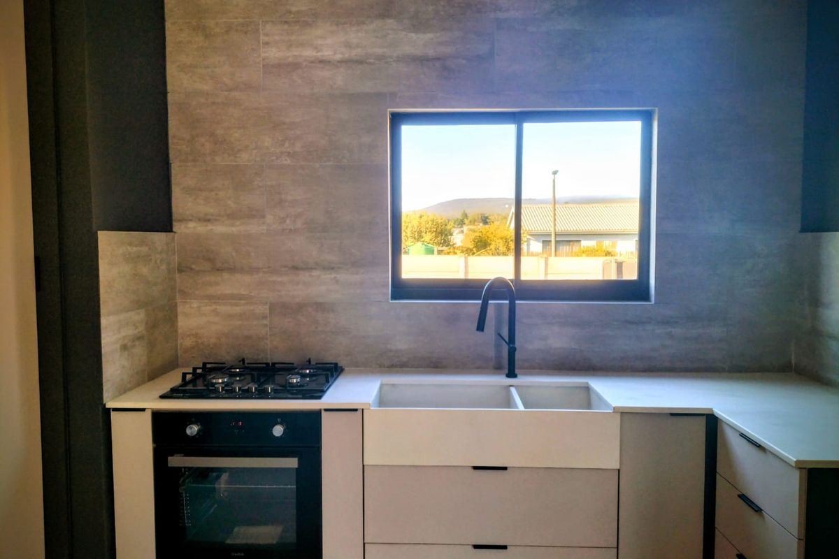 Modern kitchen featuring a built-in oven, gas hob, double basin sink with matte black faucet, and stylish stone-look wall tiling.