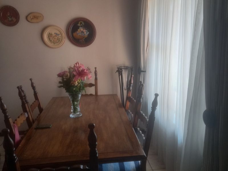 A dining room featuring tiled flooring and natural light through large windows with installed curtain tracks.