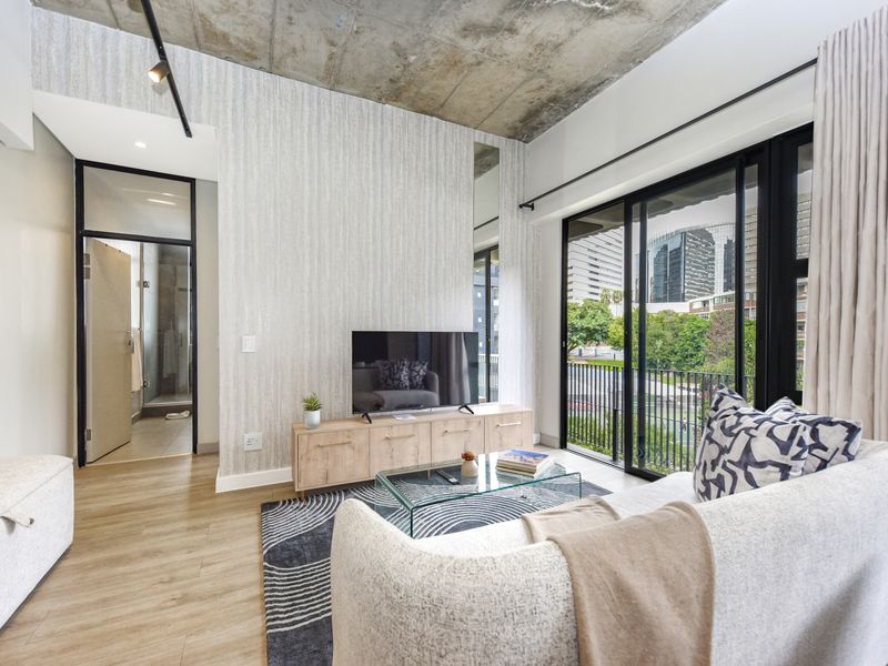 Modern living room featuring an exposed concrete ceiling, textured feature wall, and large sliding glass doors leading to a balcony with urban views.