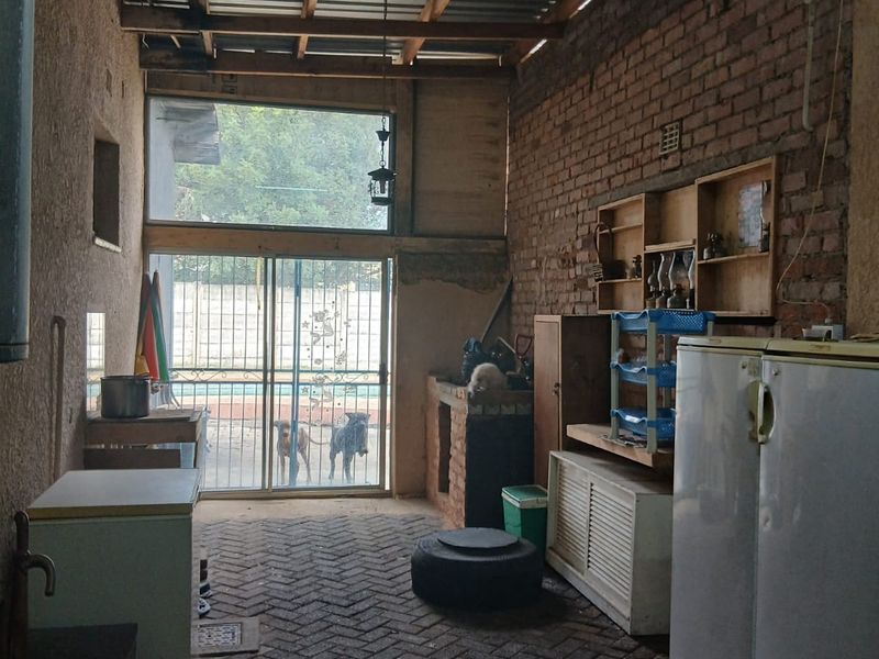 A rustic scullery or utility area featuring exposed brick walls, timber roof trusses, and direct access to the outdoor pool area.