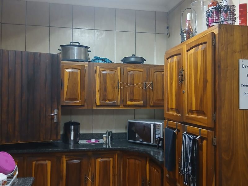 A functional kitchen featuring traditional wooden cabinetry, granite countertops, and tiled finishes, offering a classic layout with ample storage space.