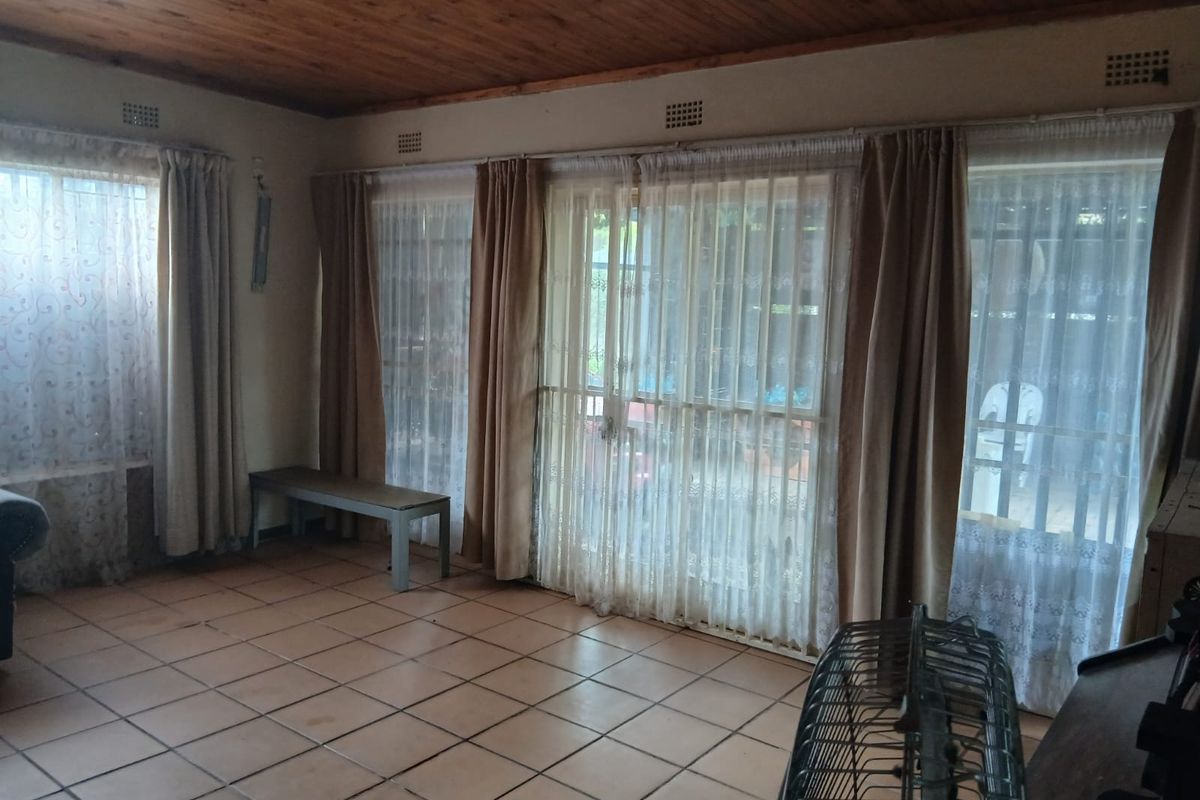 Spacious living area featuring ceramic floor tiles, a timber-clad ceiling, and large sliding glass doors providing access to the outdoor area.