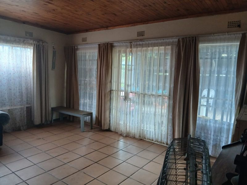 Spacious living area featuring ceramic floor tiles, a timber-clad ceiling, and large sliding glass doors providing access to the outdoor area.