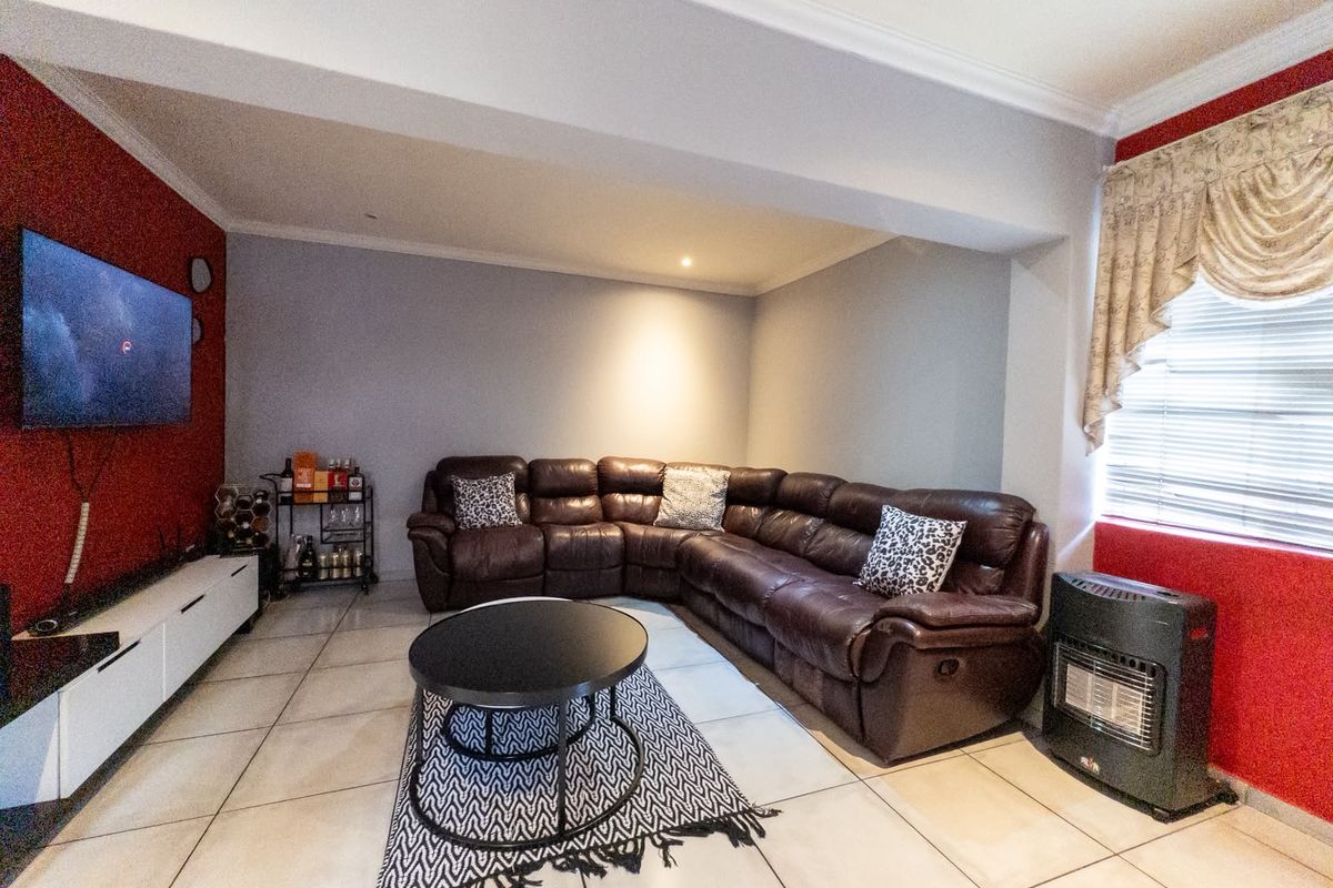 A spacious living room featuring tiled flooring, recessed downlighting, and a built-in gas heater, providing a comfortable and functional living space.