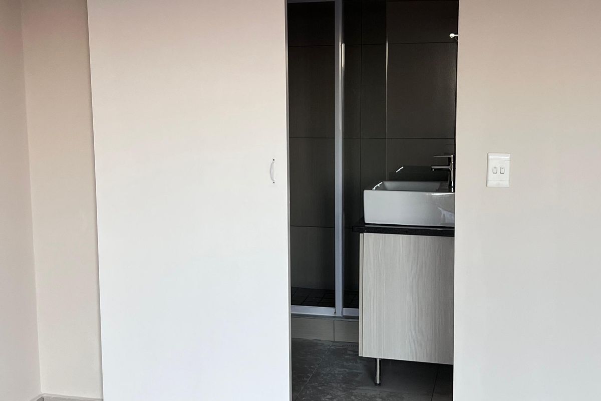 A modern bathroom featuring a sliding door entry, a contemporary vessel sink with vanity cabinet, and a tiled shower enclosure.