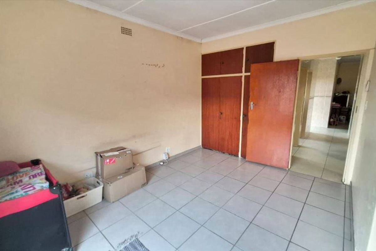 A vacant bedroom featuring tiled flooring and built-in wooden cupboards, offering a blank canvas for renovation or interior design updates.