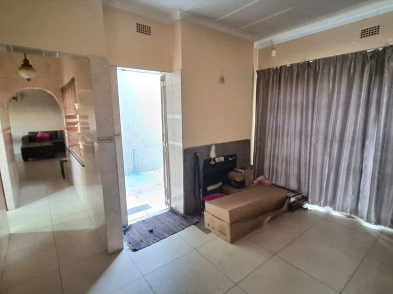 Living area featuring tiled flooring, an archway leading to an adjacent room, and a sliding door providing access to the exterior.