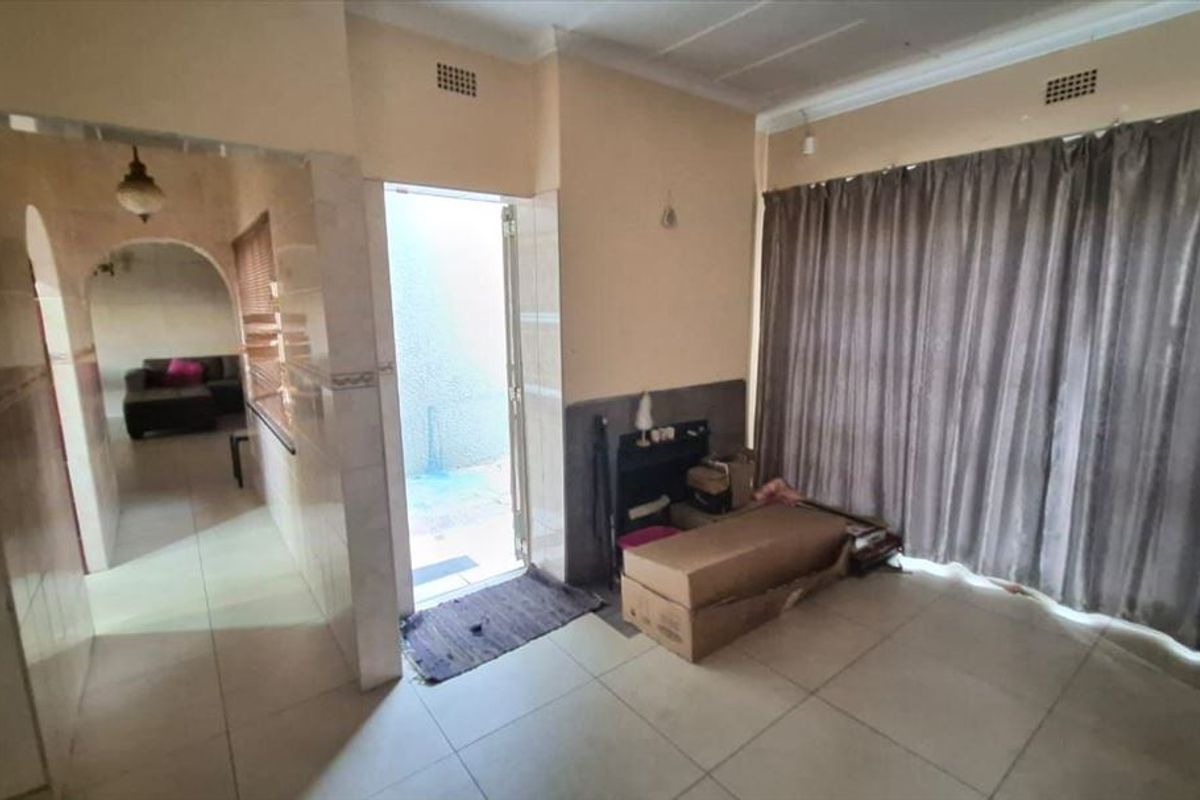 Living area featuring tiled flooring, an archway leading to an adjacent room, and a sliding door providing access to the exterior.