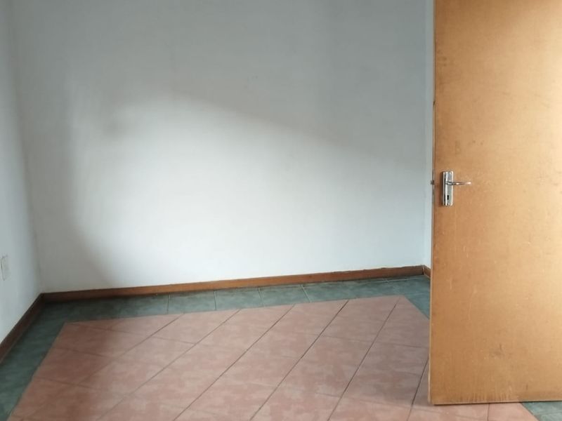 An empty bedroom featuring tiled flooring and a painted ceiling, providing a blank canvas for potential interior design updates.