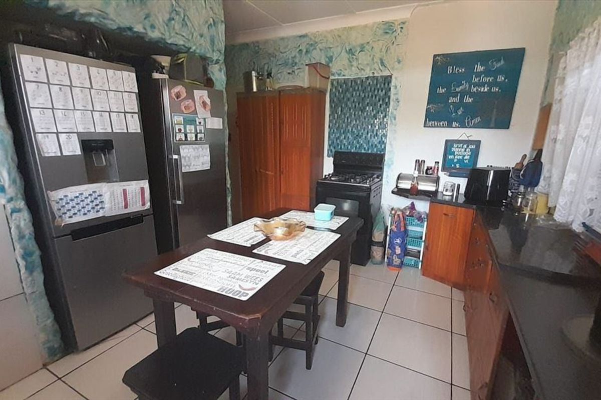 A functional kitchen featuring tiled flooring, built-in cabinetry, and a freestanding stove, offering potential for modernization and aesthetic updates.