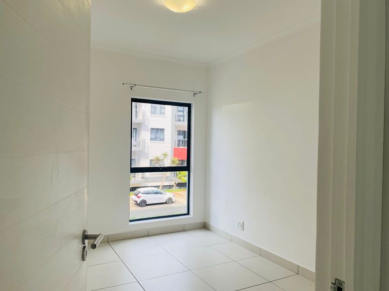 A bright, empty bedroom featuring neutral tiled flooring, a modern aluminium window frame, and clean white walls, ready for personalization.
