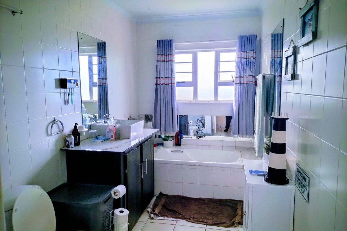 A functional bathroom featuring a built-in vanity with a vessel sink, a tiled bathtub surround, and full-height wall tiling.