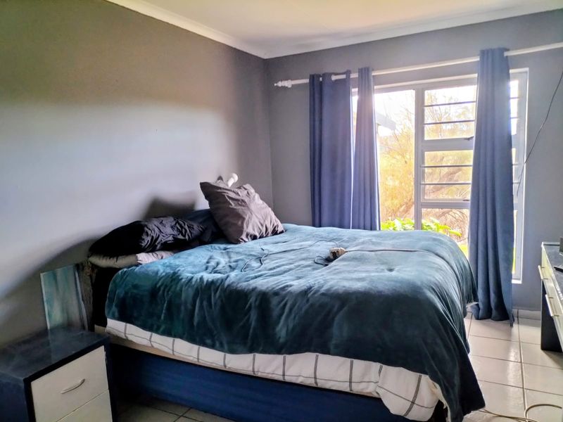 A bedroom featuring tiled flooring and a sliding glass door with security bars, providing natural light and access to the exterior.