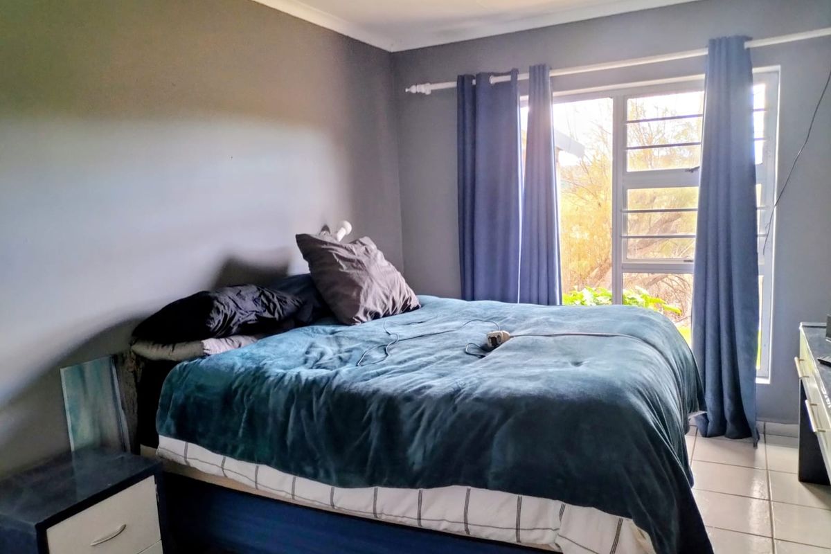 A bedroom featuring tiled flooring and a sliding glass door with security bars, providing natural light and access to the exterior.