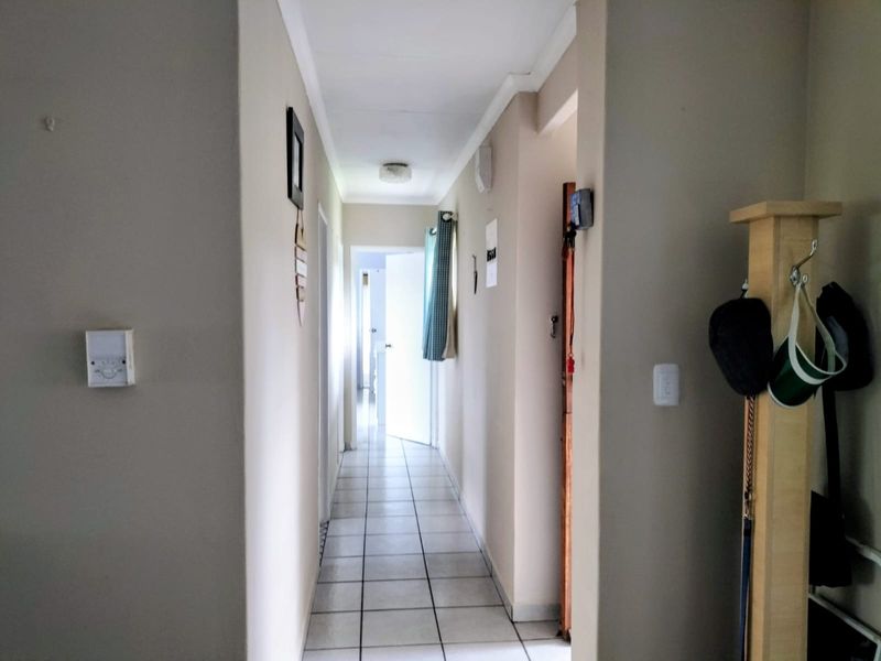 A functional residential hallway featuring neutral wall tones and tiled flooring, providing access to multiple rooms within the home.