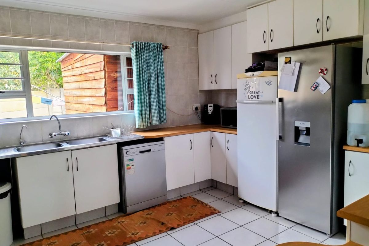 A functional kitchen featuring white cabinetry, laminate countertops, a double basin sink, and tiled flooring with a tiled splashback.