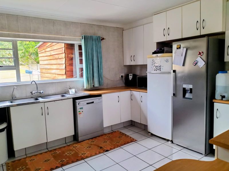 A functional kitchen featuring white cabinetry, laminate countertops, a double basin sink, and tiled flooring with a tiled splashback.