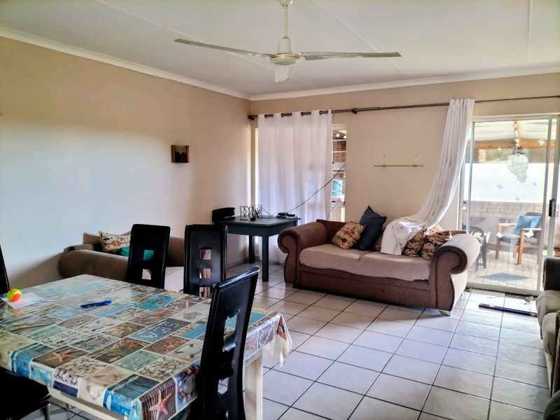 Open-plan living and dining area featuring tiled flooring, a ceiling fan, and sliding glass doors providing access to the patio.