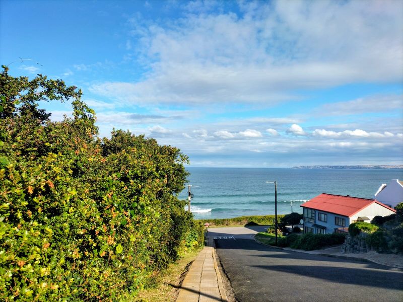 A scenic view looking down a residential street towards the ocean, showcasing the coastal location and surrounding landscape.