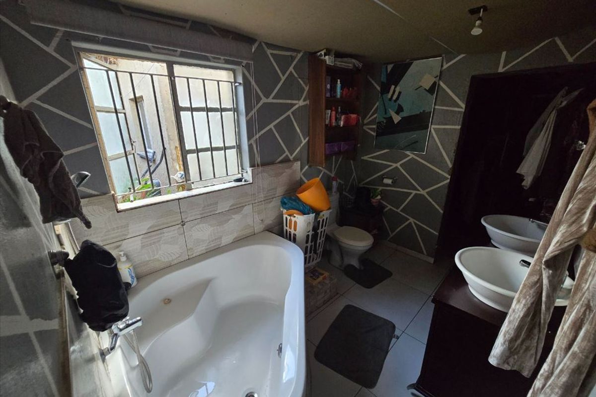A bathroom featuring a corner bathtub, dual vanity basins, and tiled finishes, requiring cosmetic updates to modernize the space.
