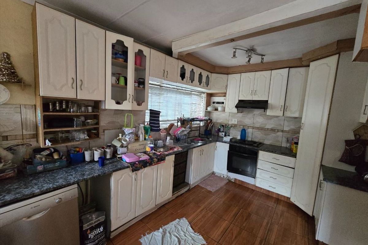 A functional kitchen featuring built-in cabinetry, laminate countertops, a built-in oven with extractor fan, and tiled flooring throughout.