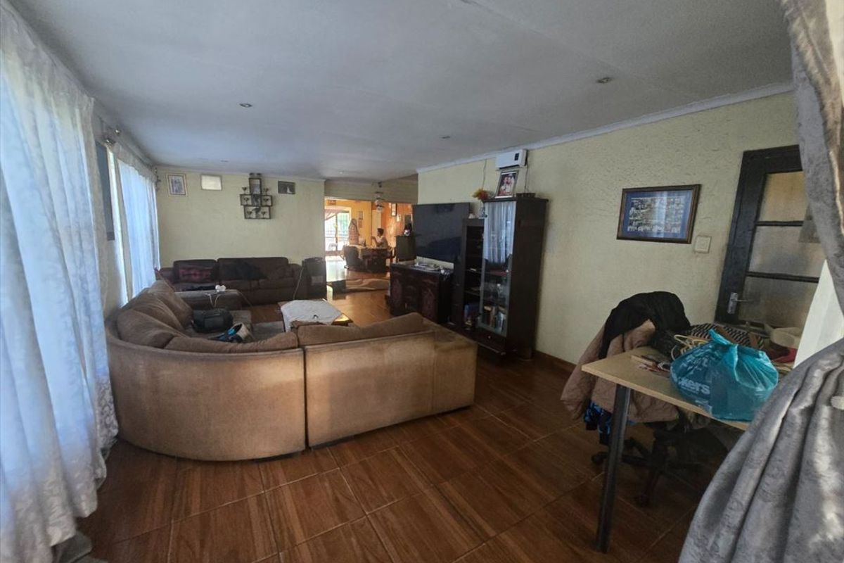 Spacious living room featuring wood-look tiled flooring, recessed ceiling lighting, and an integrated air conditioning unit.