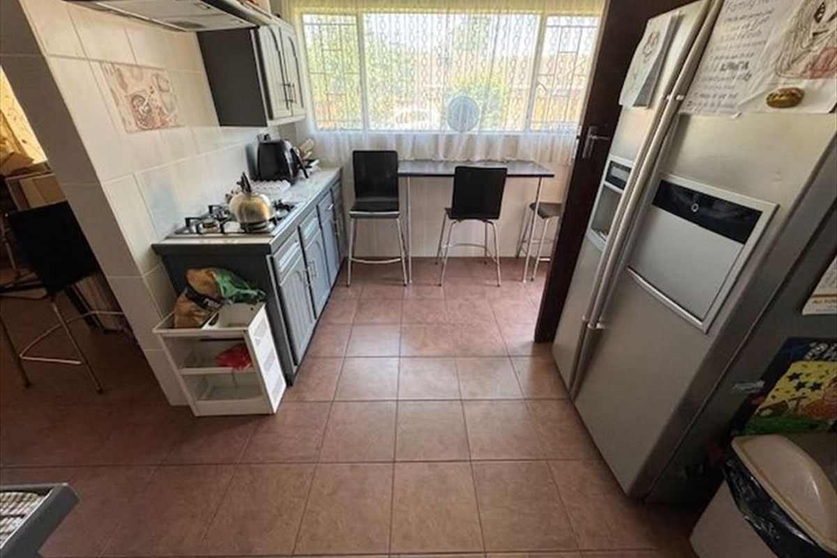 A functional kitchen featuring tiled flooring, built-in cabinetry, a gas hob with extractor fan, and a breakfast nook area.