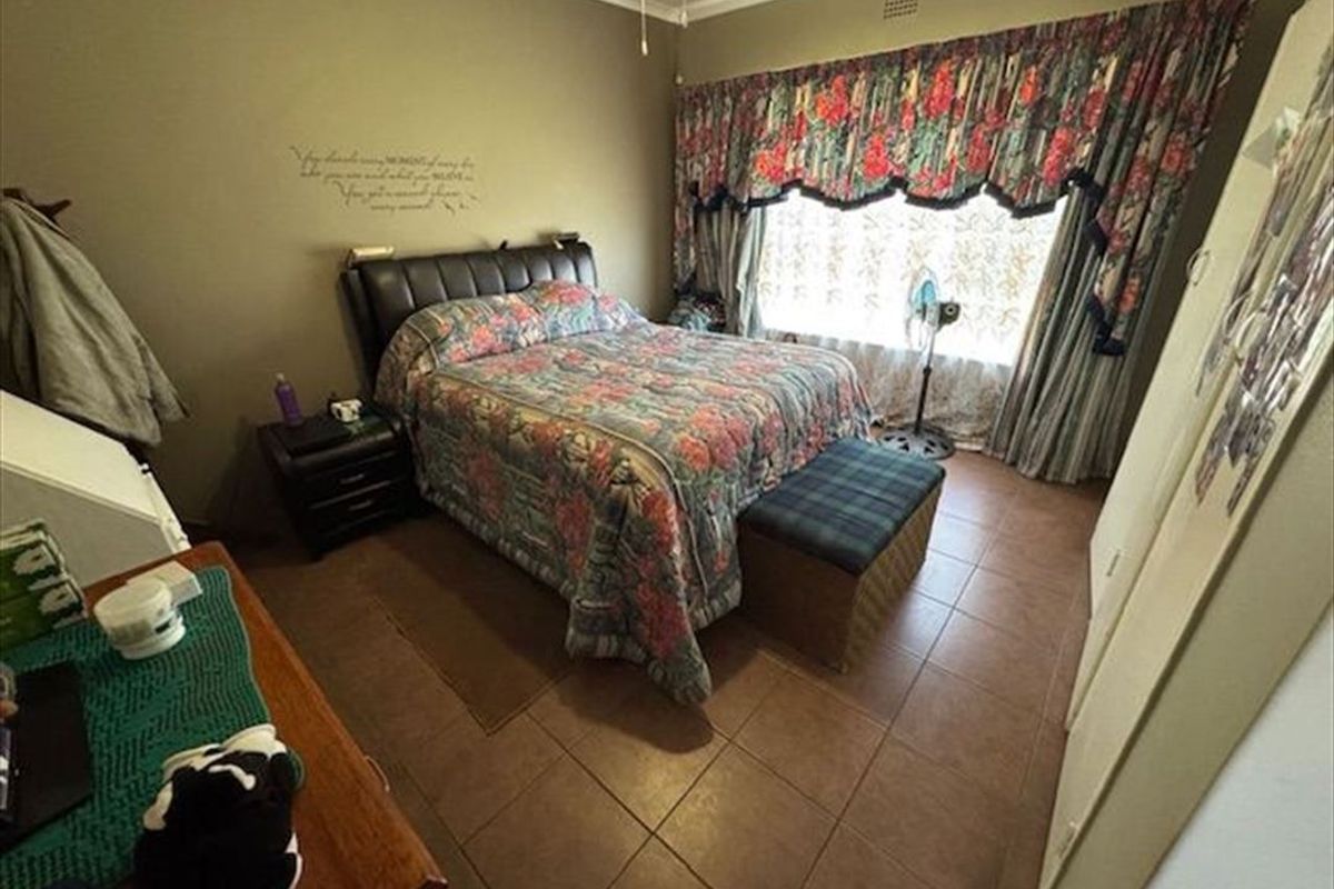 A functional bedroom featuring tiled flooring, built-in cupboards, and a ceiling fan, offering a comfortable and practical living space.