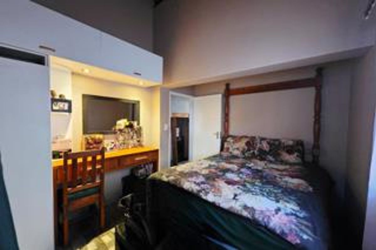 A bedroom featuring built-in cabinetry and a dedicated vanity area with integrated lighting, offering functional storage and preparation space.