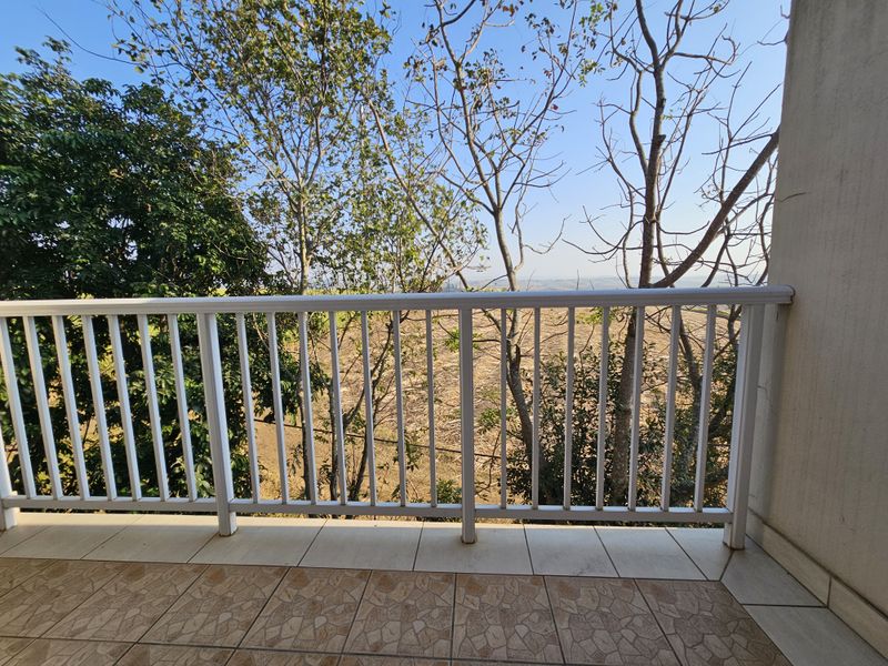 A private balcony featuring tiled flooring and a white metal balustrade, offering an open view of the surrounding landscape.