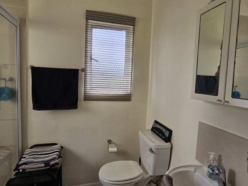 A functional bathroom featuring a shower enclosure, pedestal basin, and wall-mounted medicine cabinet, providing essential amenities in a compact layout.