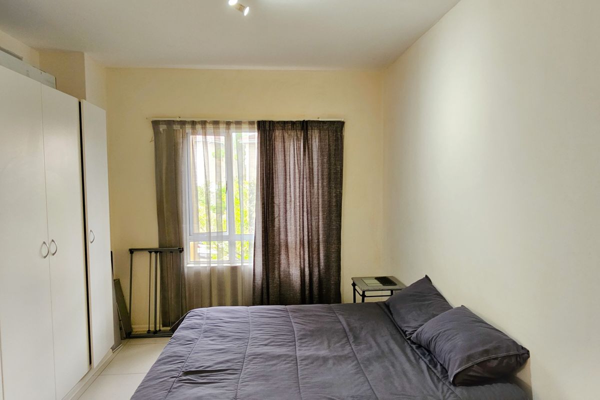 A functional bedroom featuring tiled flooring, a built-in wardrobe, and a window allowing natural light.