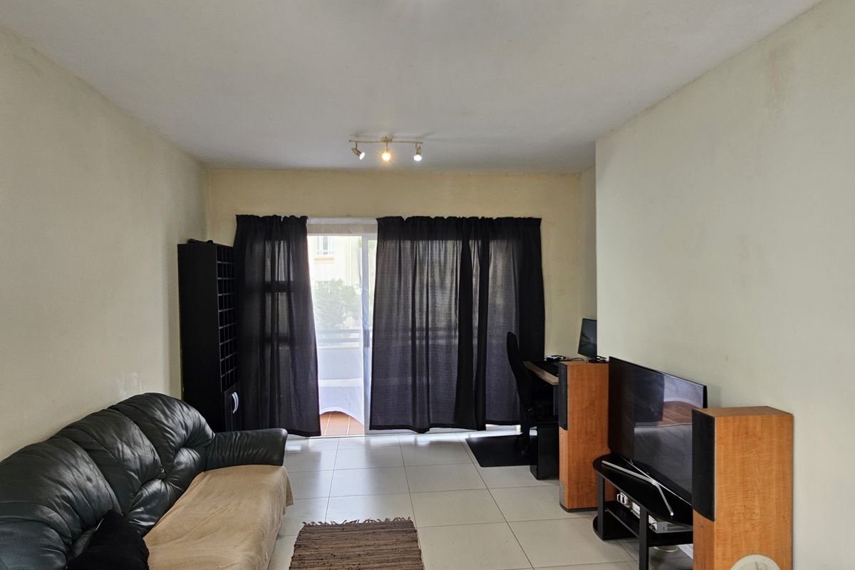 A living room featuring tiled flooring and a sliding glass door leading to a balcony, with track lighting and neutral wall finishes.