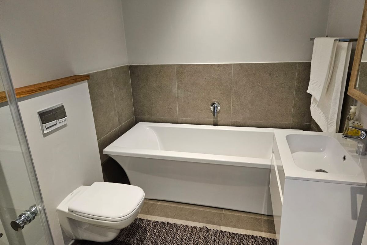 Modern bathroom featuring a wall-hung toilet with concealed cistern, a sleek freestanding bathtub, and a contemporary vanity basin with wall-mounted fixtures.