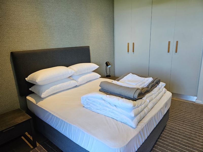 A well-maintained bedroom featuring built-in cupboards and decorative textured wallpaper, providing a clean and functional living space.
