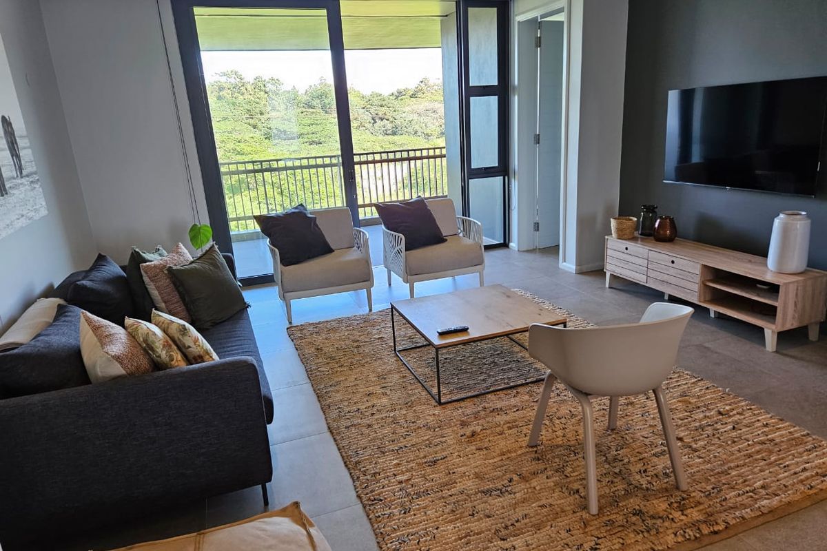 Modern living room featuring large sliding glass doors that open onto a balcony, providing ample natural light and scenic views.