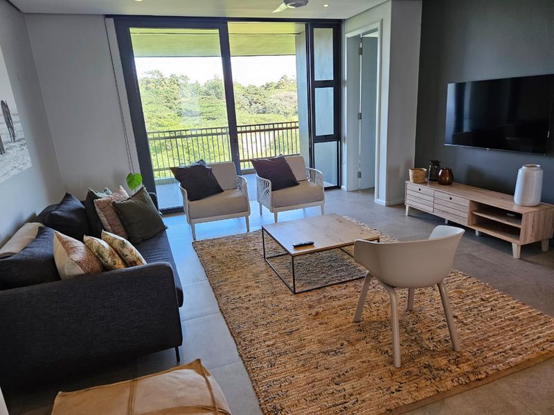 Modern living room featuring large sliding glass doors that open onto a balcony, providing ample natural light and scenic views.