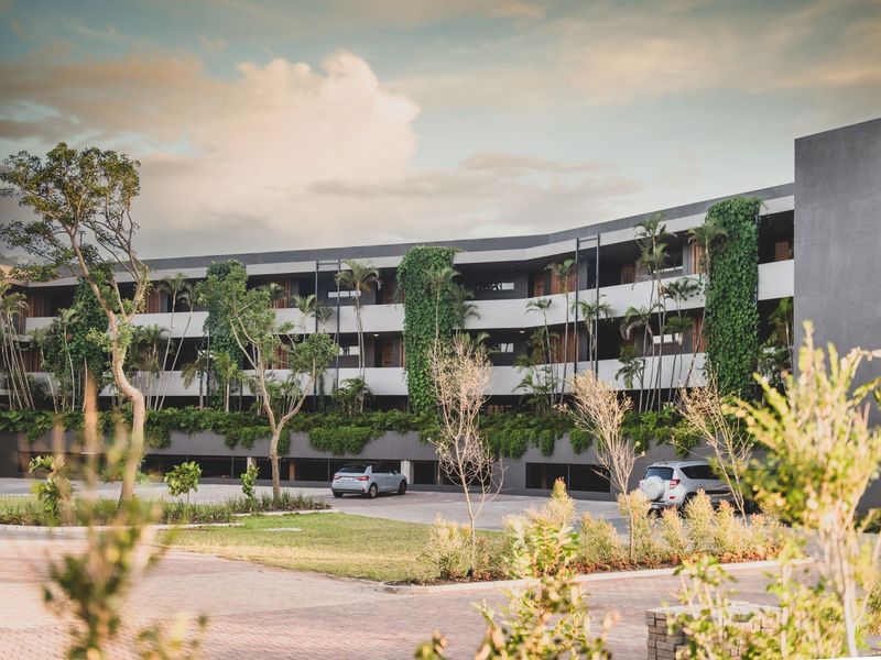 Modern apartment complex exterior featuring contemporary architecture, integrated vertical gardens, and paved parking area.
