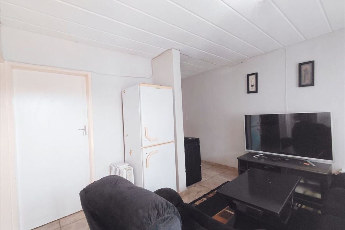 A living room area featuring tiled flooring and a panelled ceiling, requiring cosmetic updates to improve the overall aesthetic and finish.