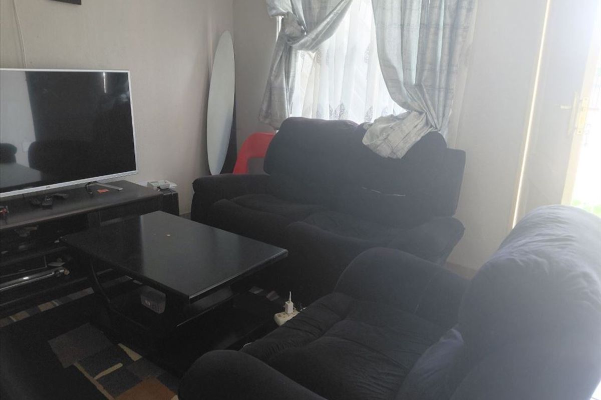 A standard living room area featuring tiled flooring and natural light from a window.