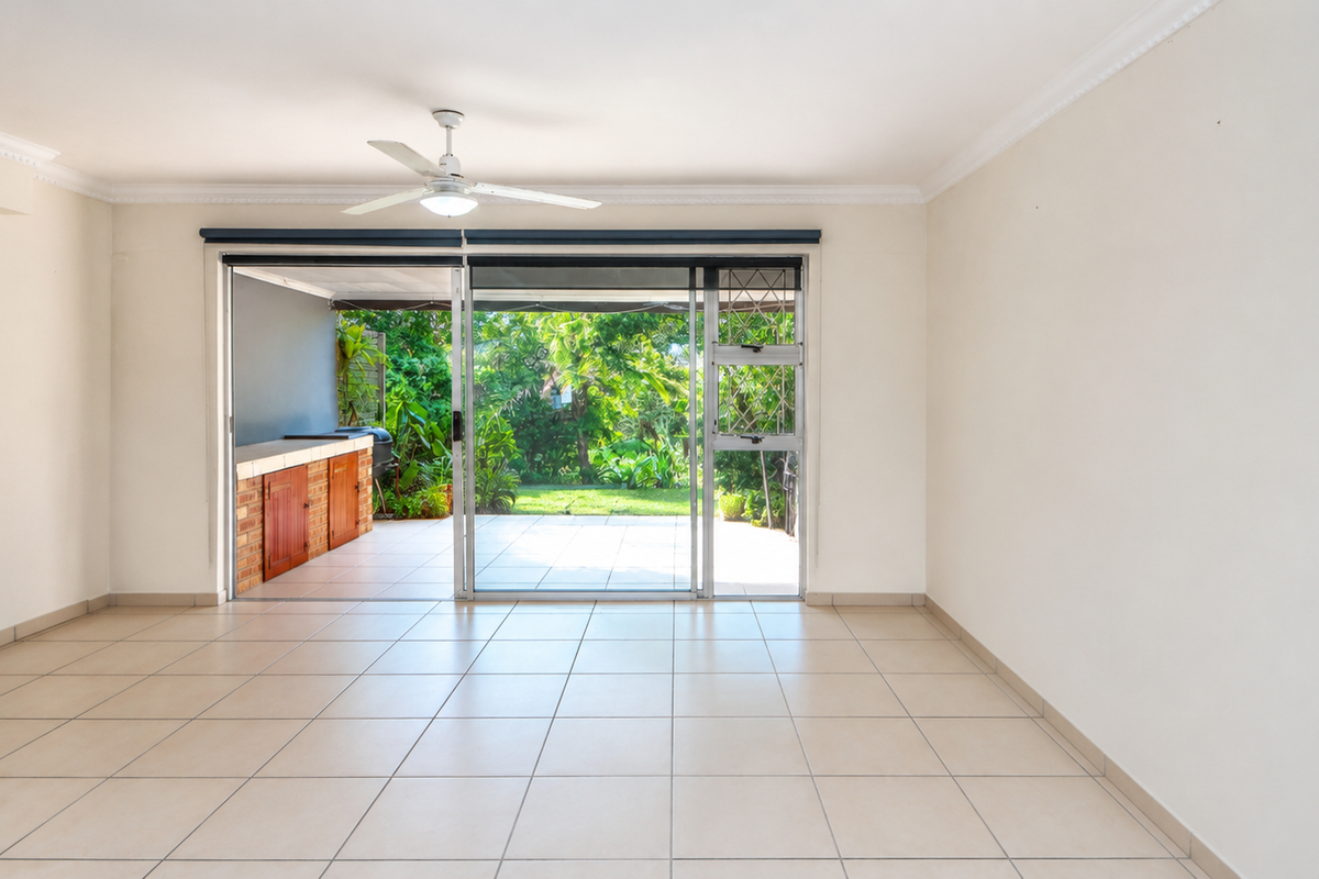 Spacious, light-filled living area featuring neutral tiled flooring, a ceiling fan, and large sliding doors providing seamless access to the outdoor patio and garden.