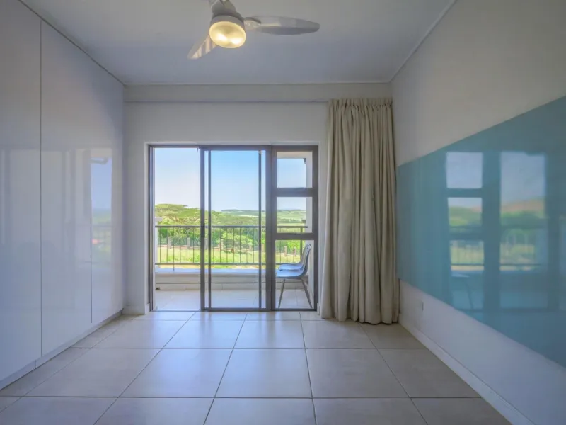 Bright bedroom featuring built-in cupboards, tiled flooring, a ceiling fan, and direct access to a private balcony with scenic views.