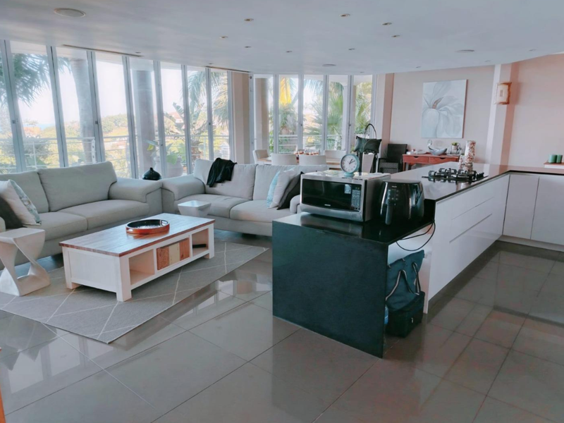 Spacious open-plan living area featuring a modern kitchen with a large island, gas hob, and expansive floor-to-ceiling windows providing natural light.