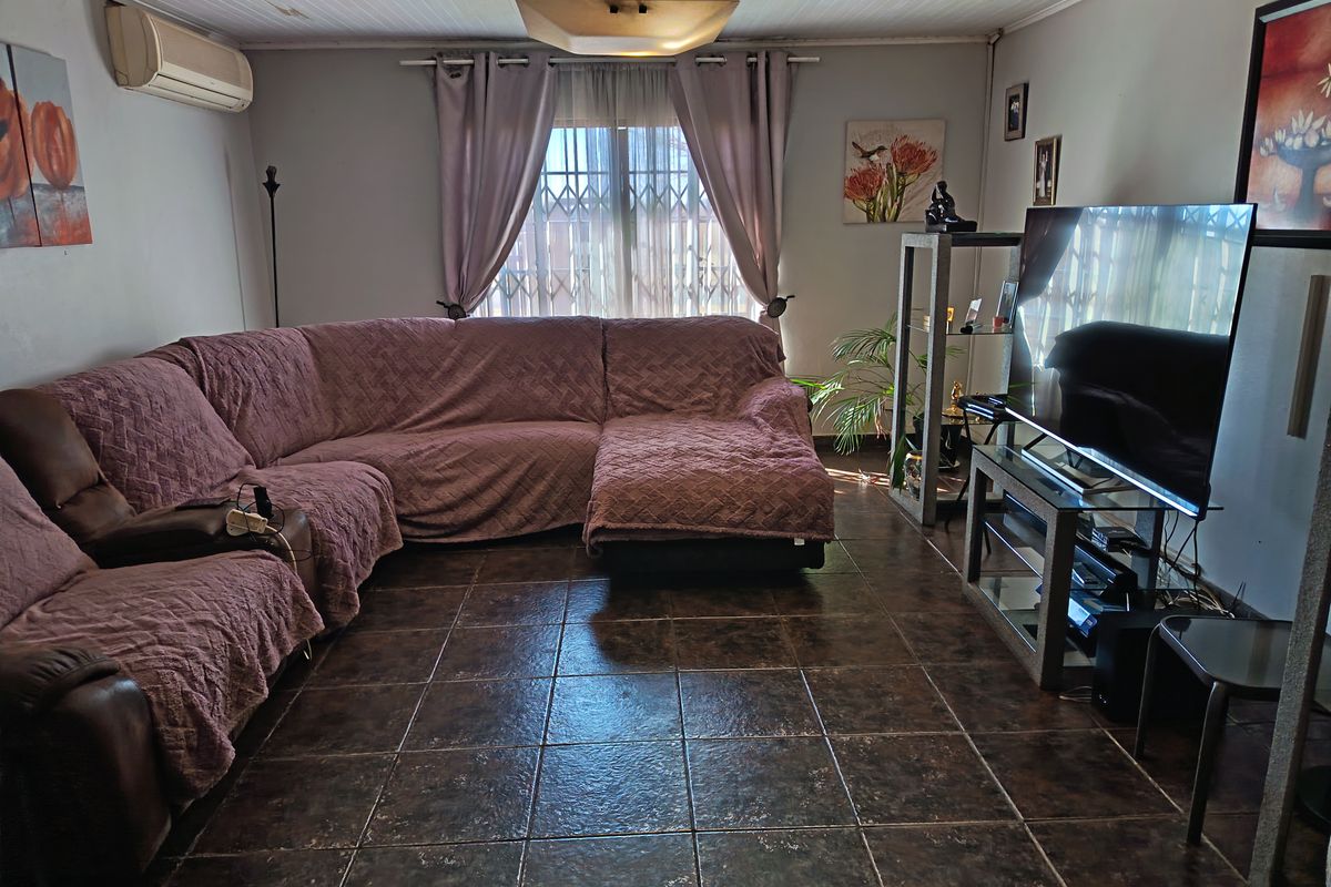 A living room featuring tiled flooring, a timber panel ceiling, and a wall-mounted air conditioning unit.