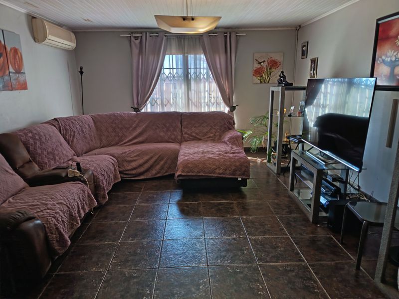 A living room featuring tiled flooring, a timber panel ceiling, and a wall-mounted air conditioning unit.
